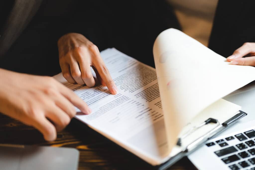Signature de contrat : Comment bien réviser vos documents Main pointant un formulaire de consentement lors d'une révision de contrat professionnelle au bureau.