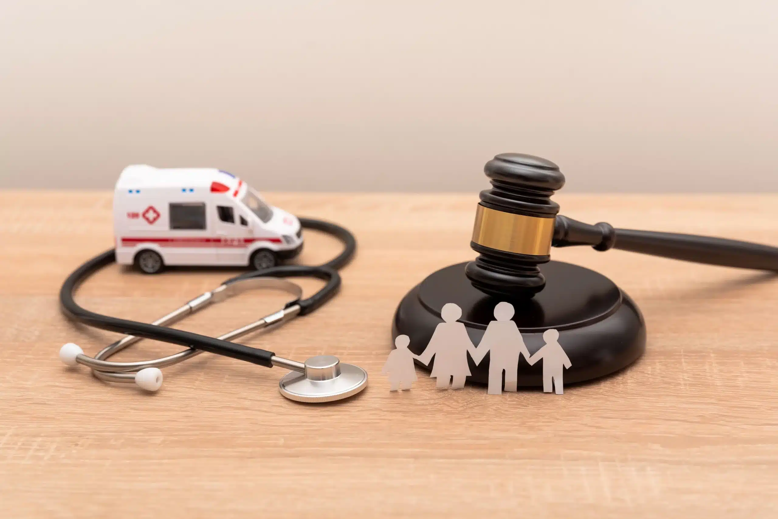Gavel de juge, stéthoscope, ambulance et famille en papier illustrant le droit médical et les litiges de santé.